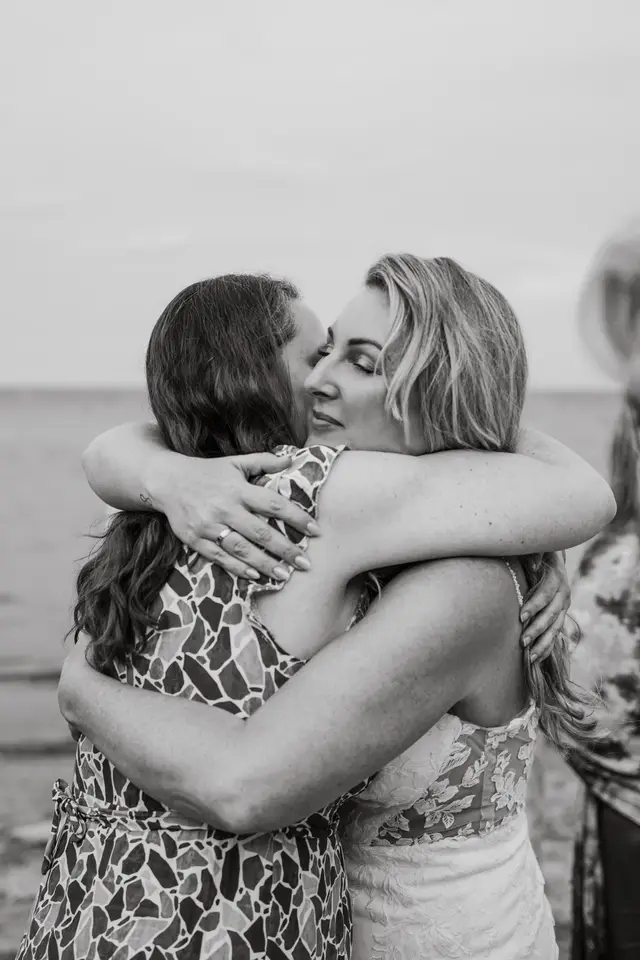 La novia abraza emocionada a una invitada, en blanco y negro