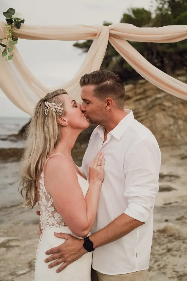 Beso de los novios bajo el arco de tul