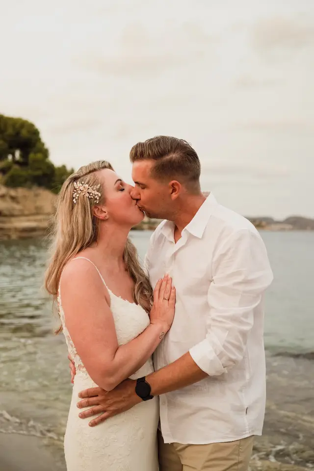 Beso de los novios en la orilla con la luz de la tarde