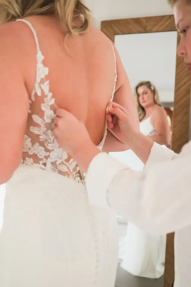 Abrochando los botones de la espalda de encaje del vestido de novia
