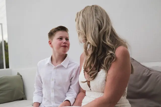 La novia sonríe a un niño sentado a su lado antes de la ceremonia