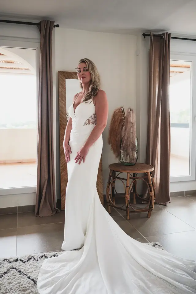 La novia ya vestida en la habitación, con la cola del vestido extendida en el suelo