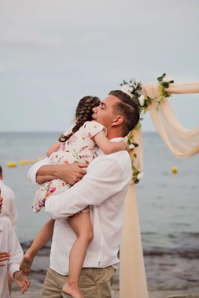 El novio abraza a una niña junto al arco de la ceremonia