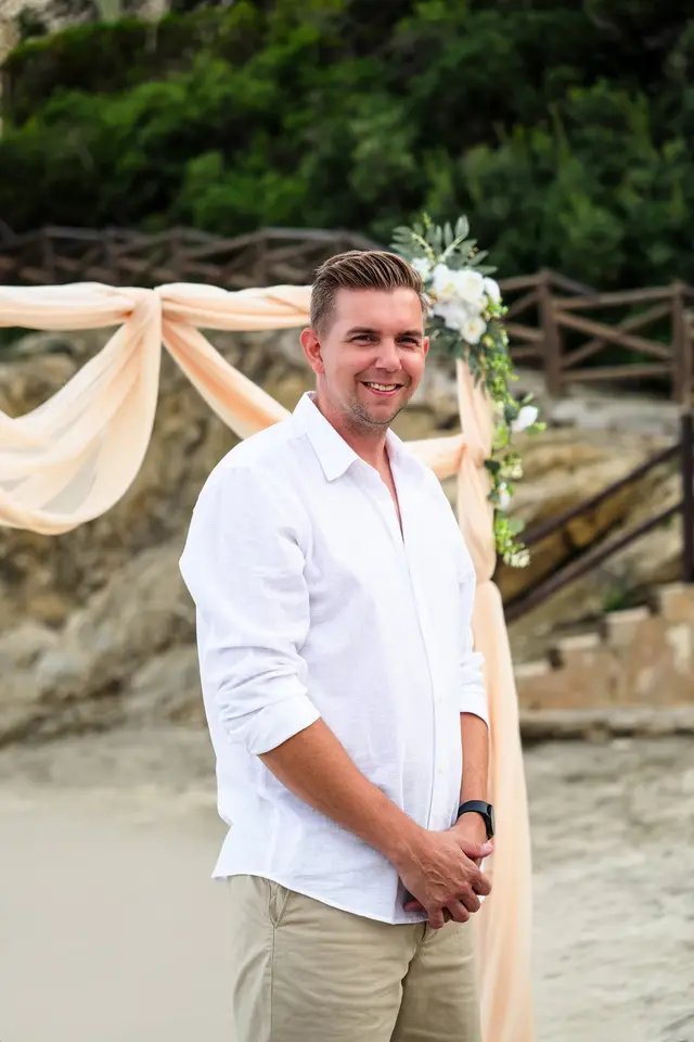 El novio espera sonriente junto al arco