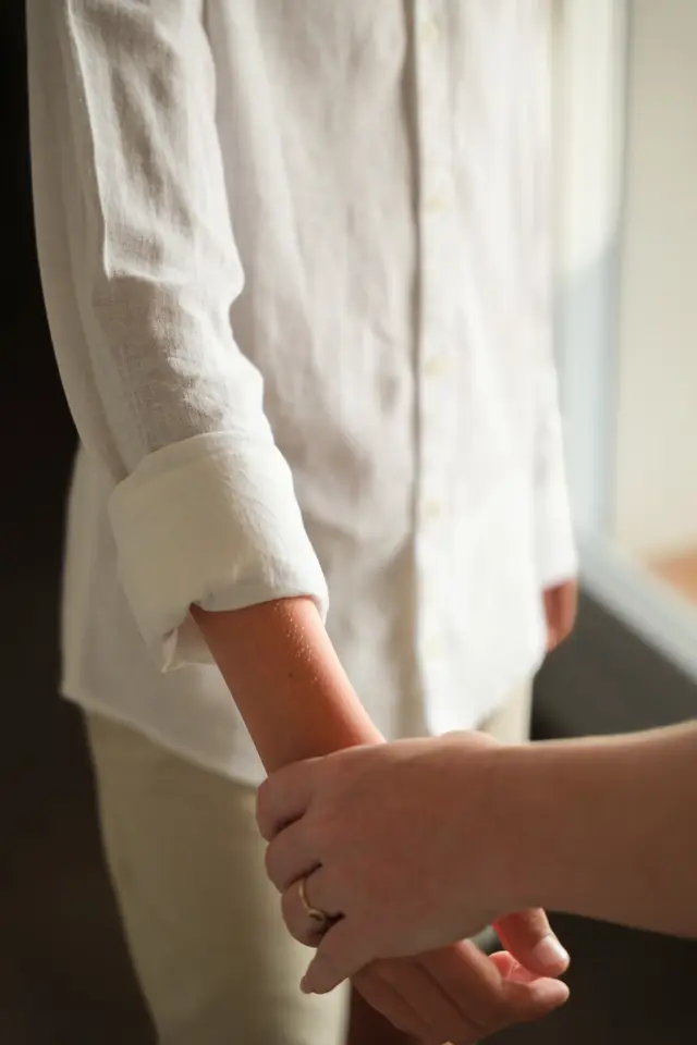 Manos abrochando el puño de la camisa blanca de un niño antes de la boda