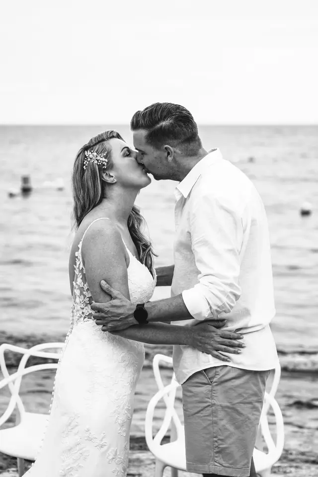 Los novios se besan al encontrarse junto al mar, en blanco y negro