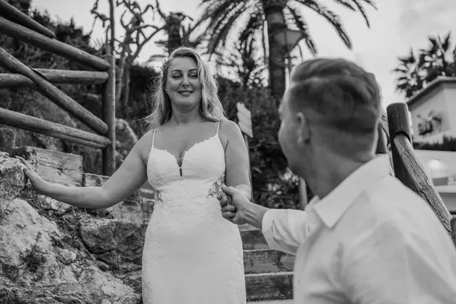 La novia sonríe al novio al encontrarse en el camino a la cala, en blanco y negro