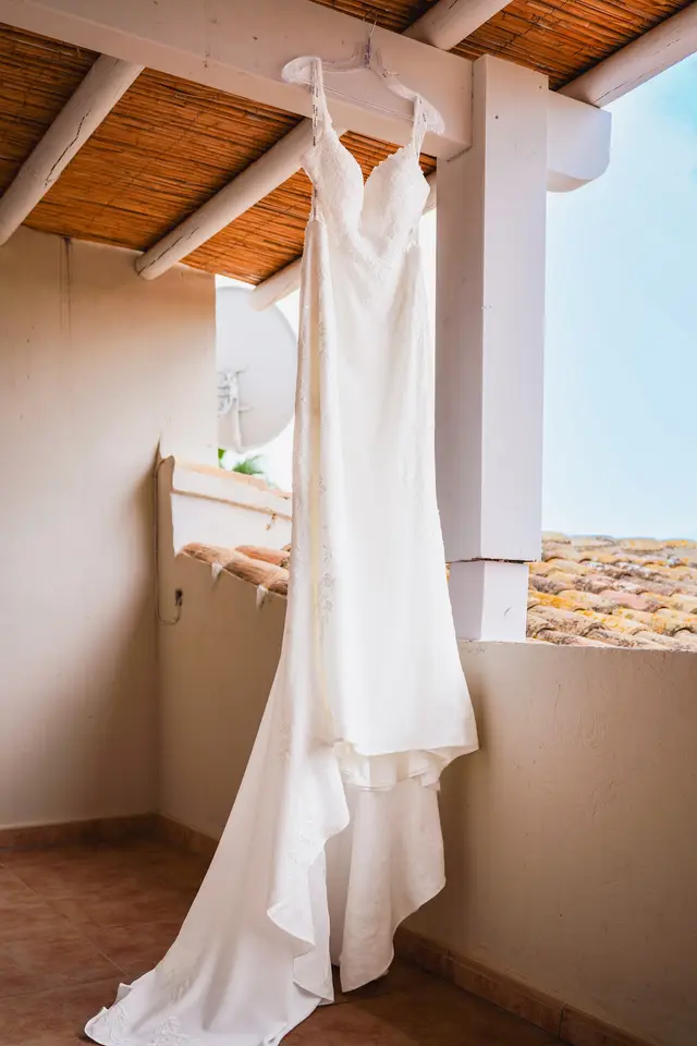 Vestido de novia colgado en un porche con tejado de cañizo