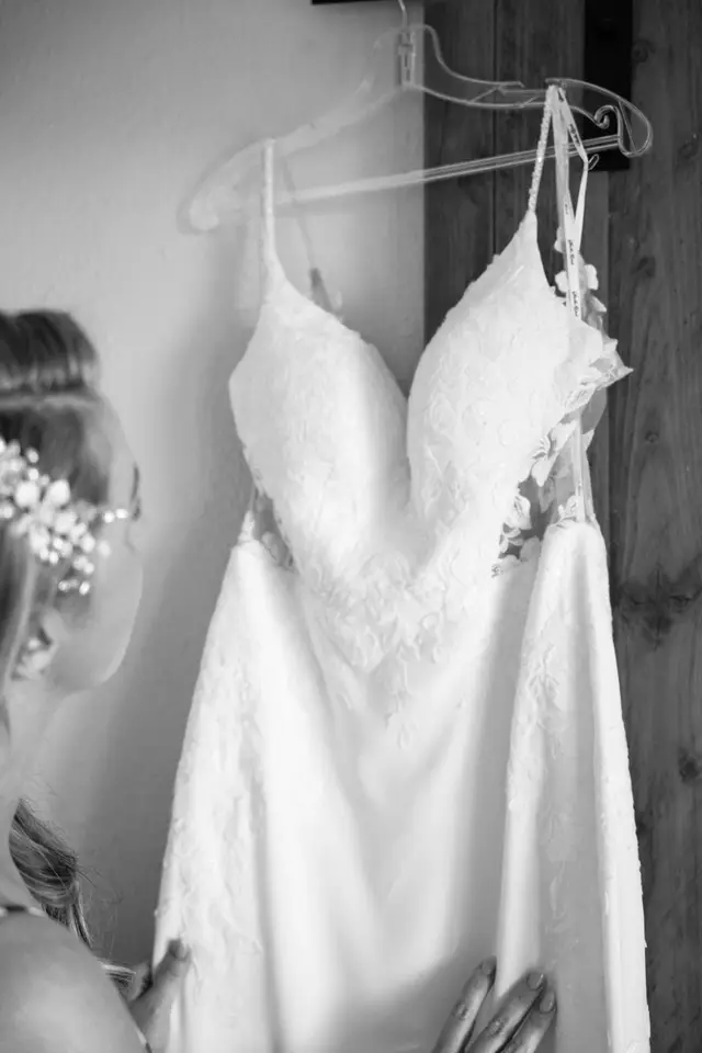 El vestido de novia colgado de una percha mientras la novia se prepara, en blanco y negro